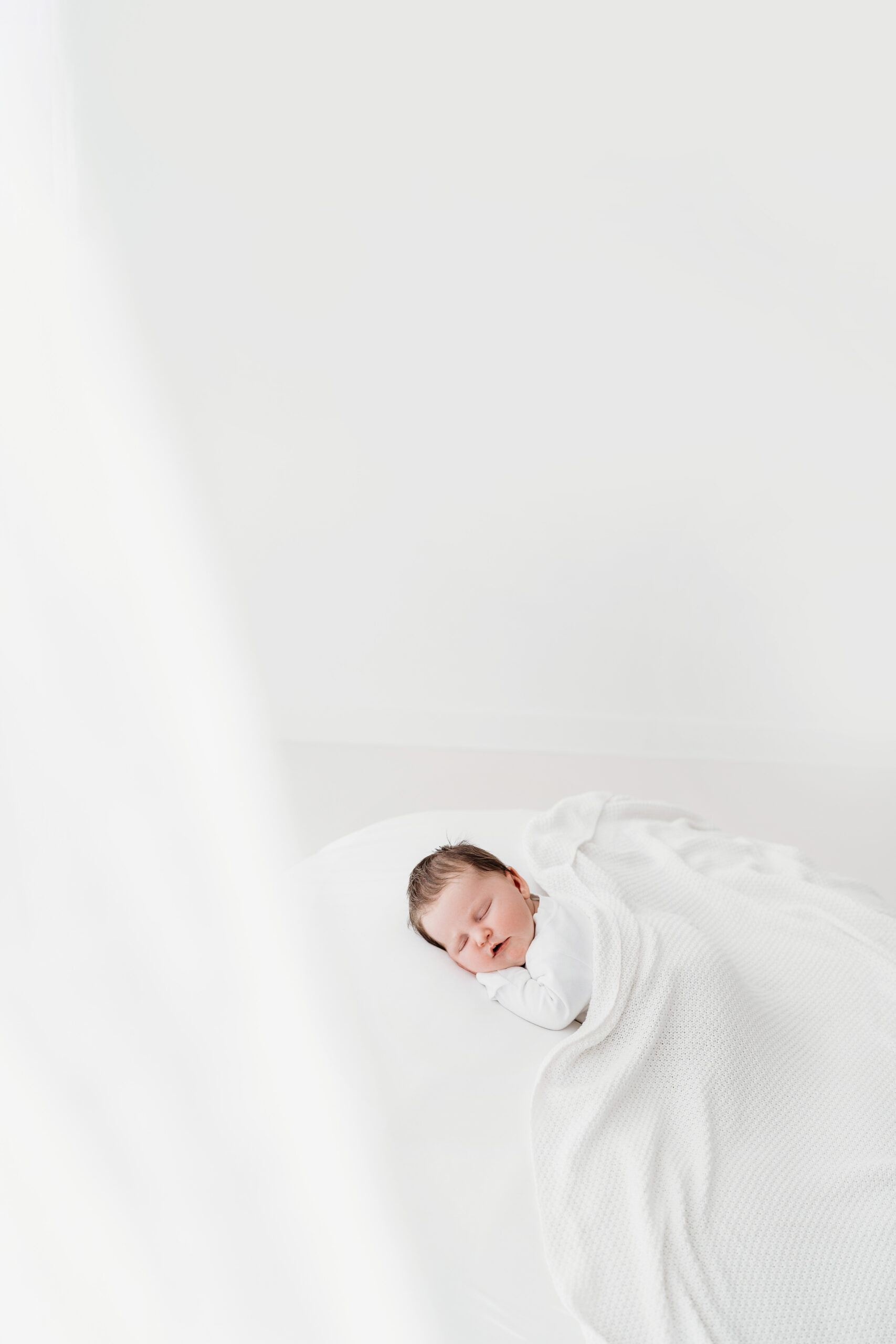 newborn girl asleep on a white bed