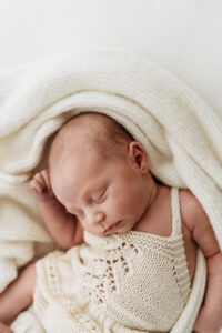 newborn girl snuggled up on a beanbag on her photoshoot near Wilmslow