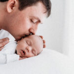 Newborn father kissing baby