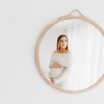 Pregnant mother looking into mirror on her maternity photoshoot.