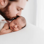 Newborn father kissing his baby on a photoshoot