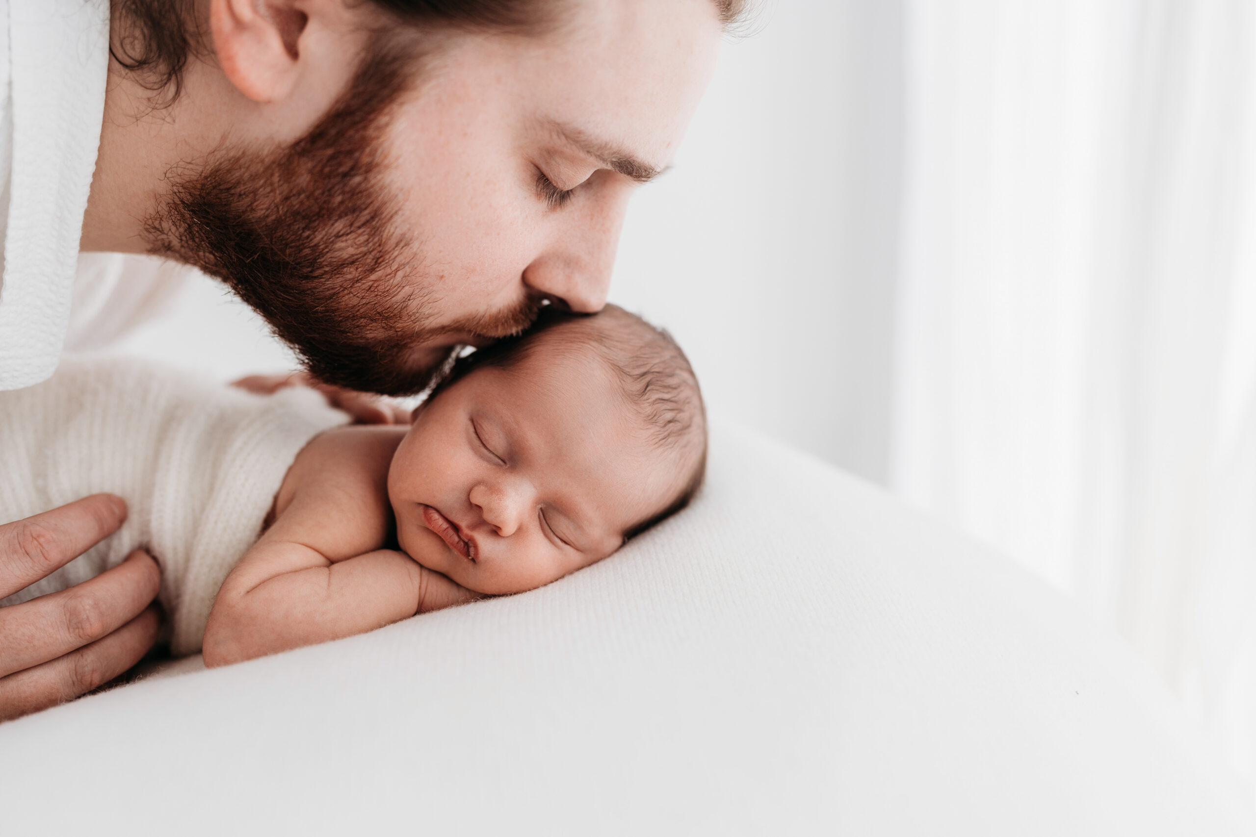 Newborn father kissing his baby on a photoshoot