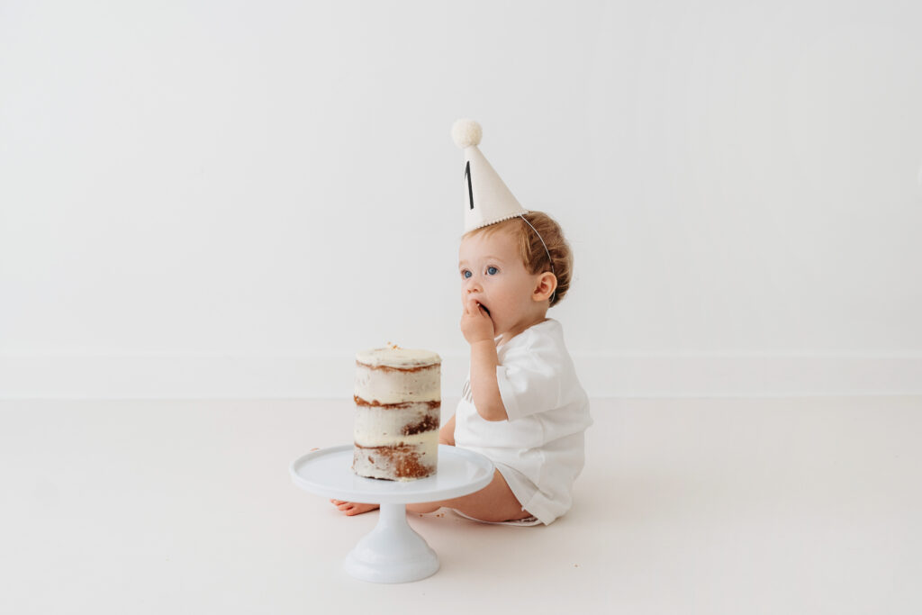 Baby boy eating cake on natural cake smash in Cheshire