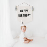 Baby boy on his cake smash photoshoot in Cheshire with party hat