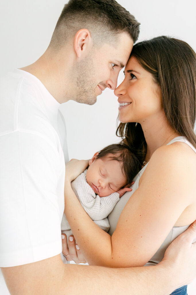 gorgeous couple cuddling with their sleeping newborn