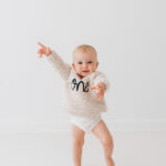 Baby girl turning one on her cake smash in cheshire in natural all white photography studio near Wilmslow