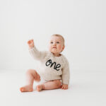 Baby boy turning one on her cake smash in cheshire in natural all white photography studio near Wilmslow