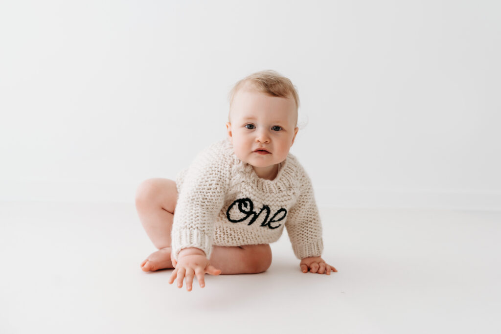 Baby boy in gorgeous ONE birthday jumper on his cake smash photoshoot in Cheshire