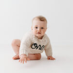 Baby boy in gorgeous ONE birthday jumper on his cake smash photoshoot in Cheshire