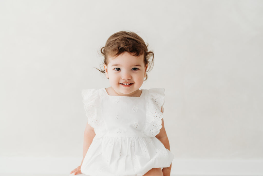 Little girl sitting on a stool looking at the camera on her toddler photoshoot in Cheshire