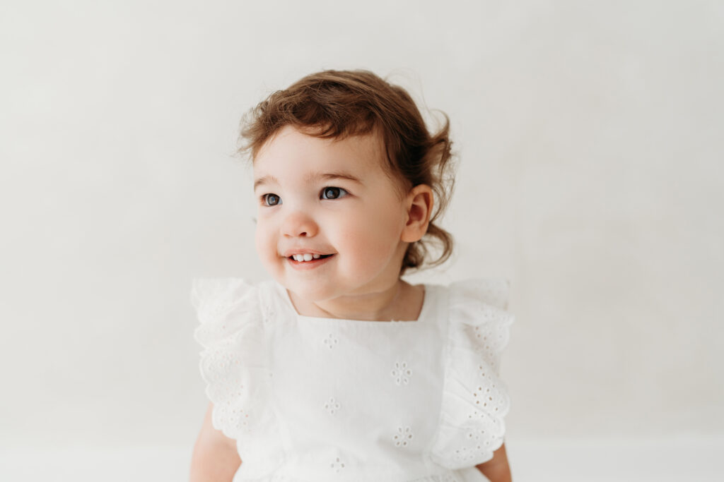 Young girl sitting on a stool looking at her mum on her toddler photoshoot in Cheshire