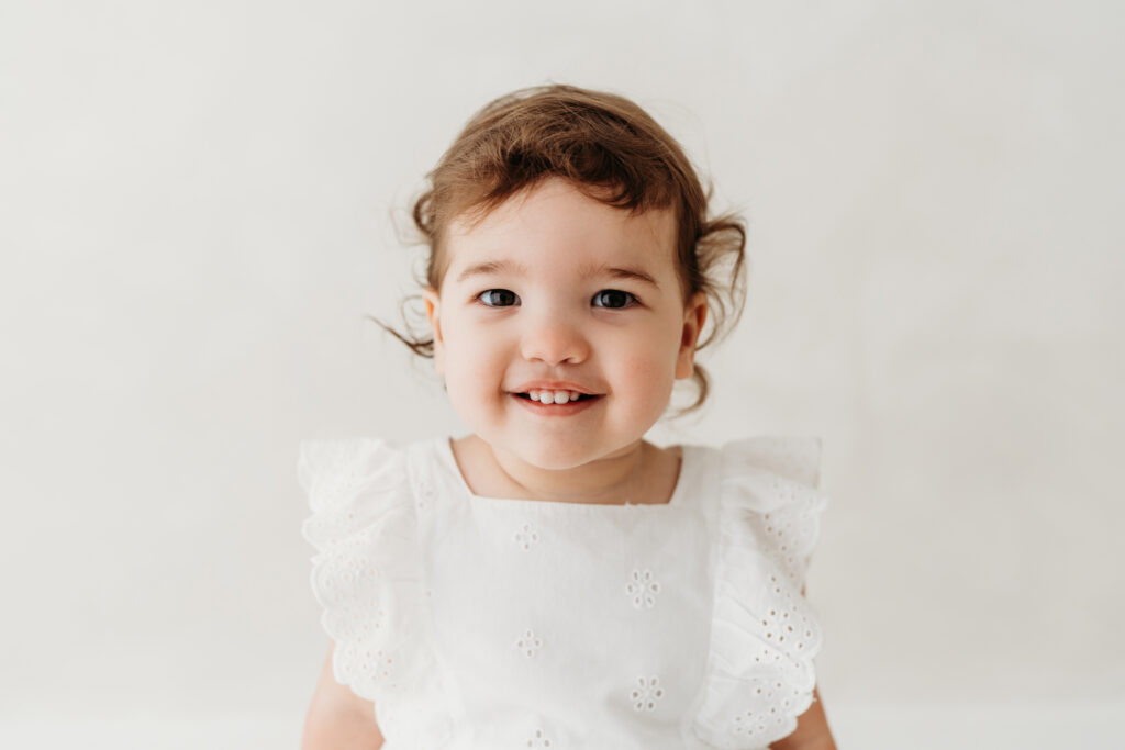 Young girl sitting on a stool looking at the camera on her toddler photoshoot in Cheshire