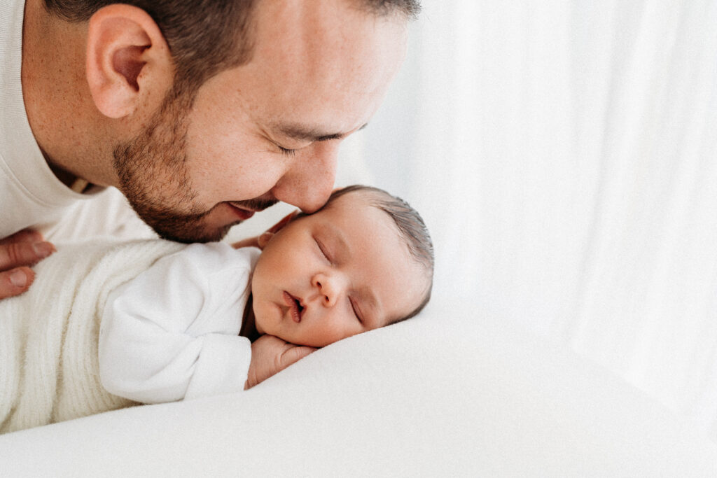 father snuggling into newborn baby on a natural baby photoshoot