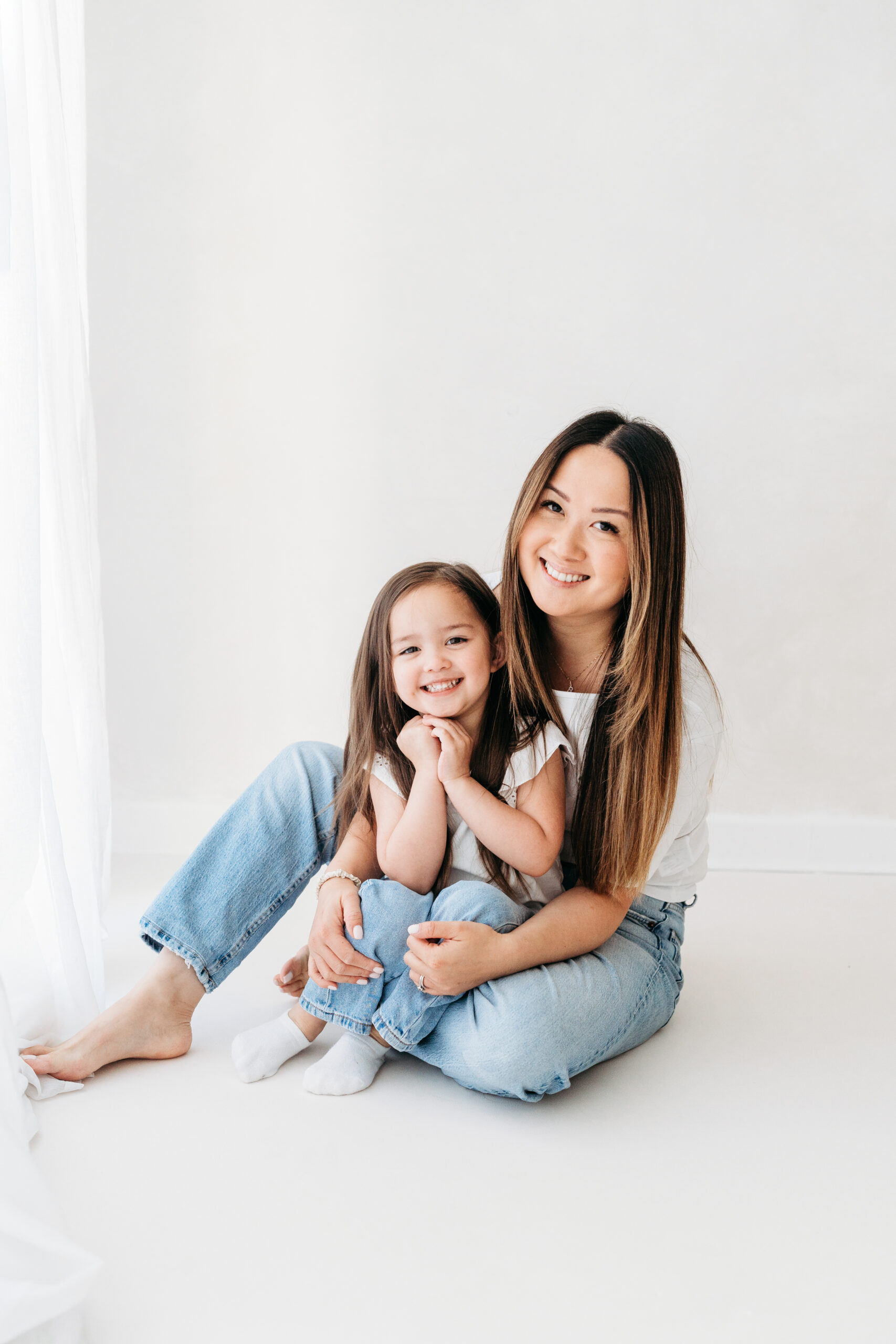 Daughter sitting on her mothers knee on a natural family photoshoot in Cheshire